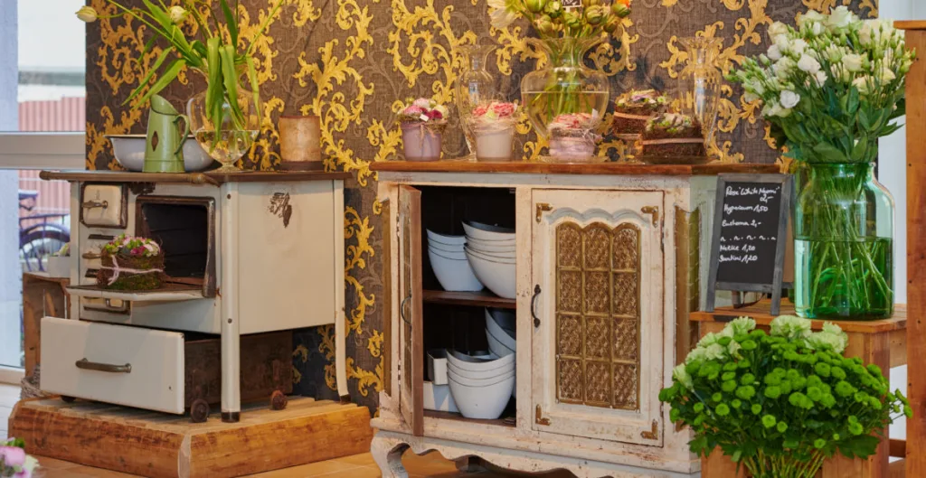 Alter weißer Küchenherd und Vintage-Anrichte mit Keramikschalen und Blumensträußen