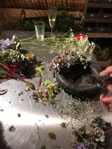 Arbeitstisch mit Hortensienblüten, Heidekraut und Schleierkraut, daneben ein Kranzrohling und eine Gartenschere
