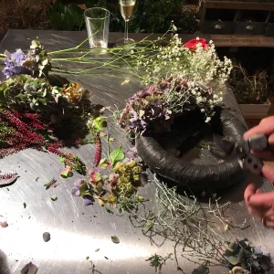 Arbeitstisch mit Hortensienbl&uuml;ten, Heidekraut und Schleierkraut, daneben ein Kranzrohling und eine Gartenschere