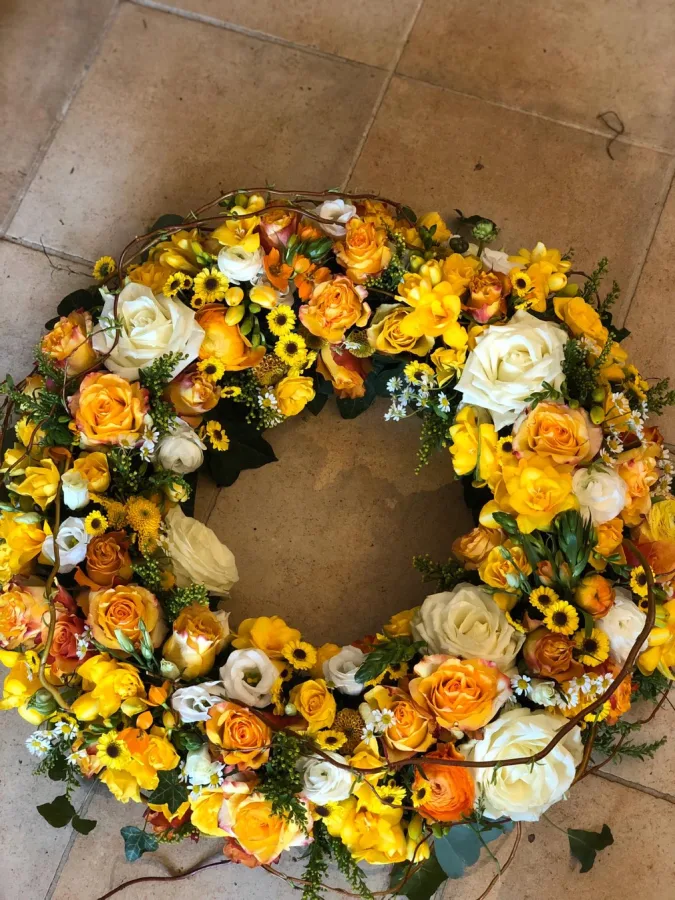 Runder Trauerkranz mit gelben und orangen Rosen, Ranunkeln und weißen Lisianthus