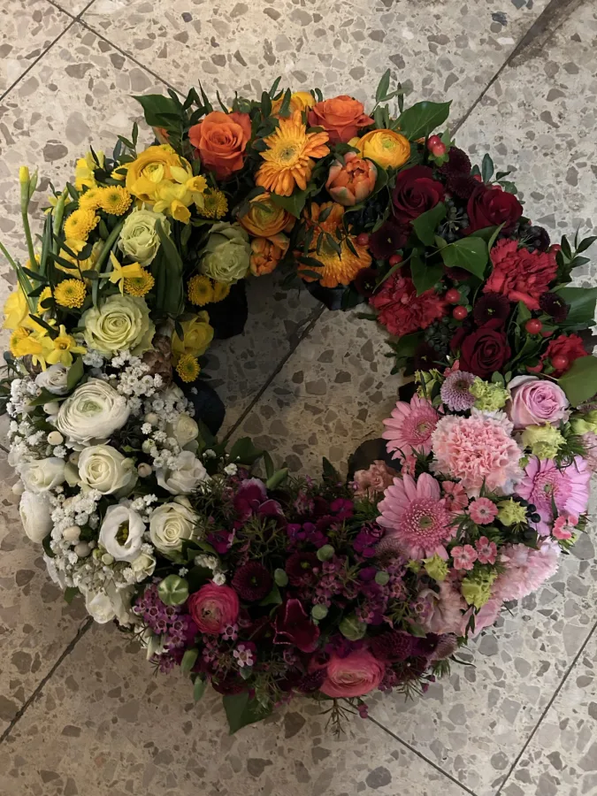 Runder Trauerkranz mit gelben, roten und pinken Rosen und Nelken