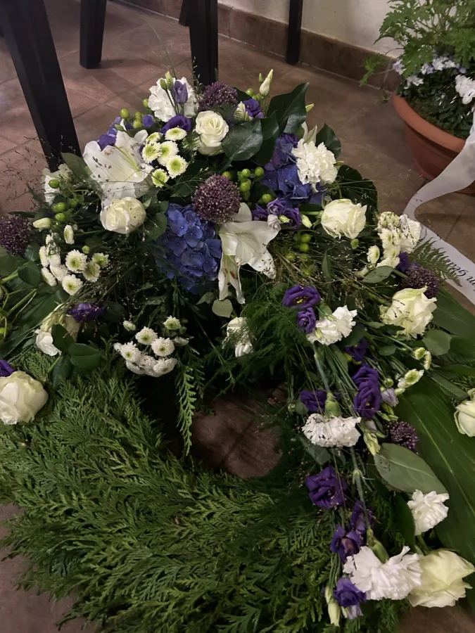 Trauerkranz aus Tannengrün mit weißen Rosen und violetten Blüten