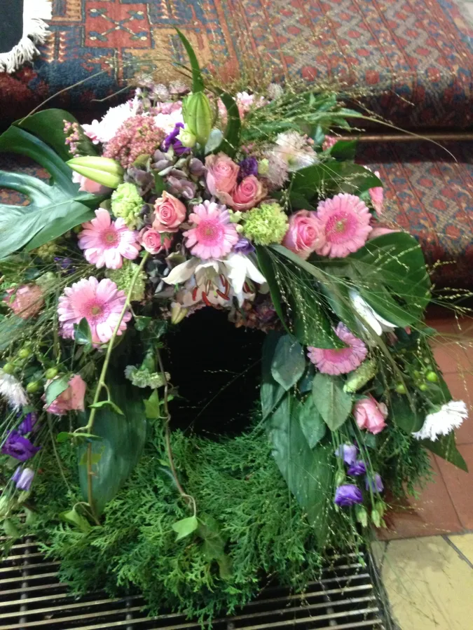 Trauerkranz aus Tannengrün mit rosa Gerbera, Nelken und weißen Lilien
