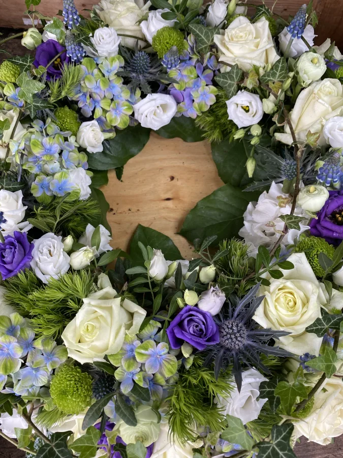 Trauergesteck mit weißen Rosen, violetten Lisianthus und Distelblüten