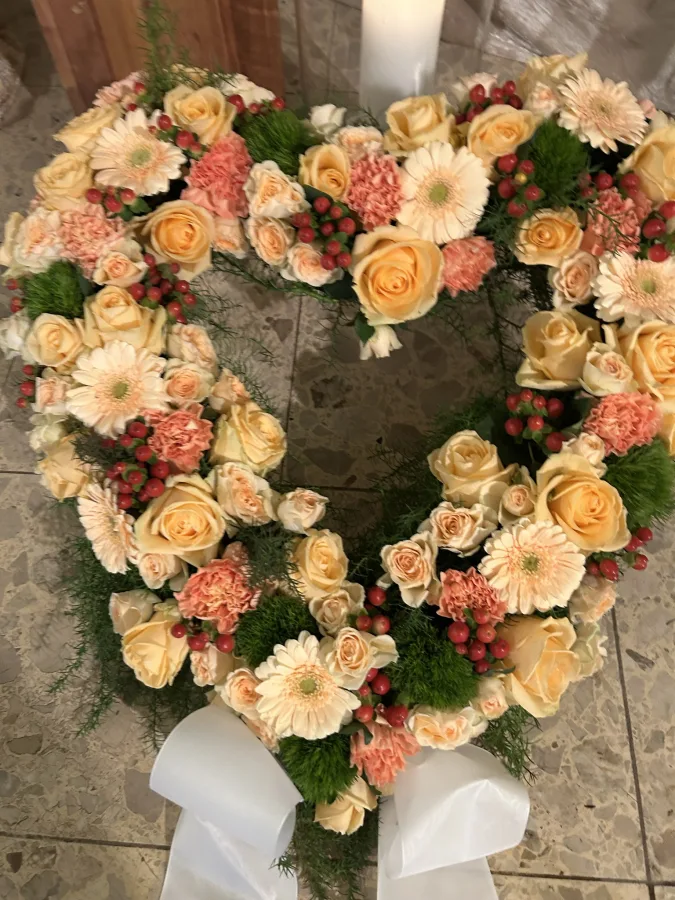 Herzförmiges Trauergesteck mit apricotfarbenen Rosen, Gerbera und Nelken