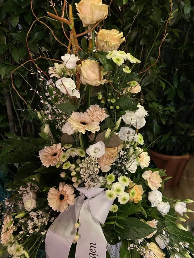 Trauergesteck mit cremefarbenen Rosen, Gerbera und weißer Trauerschleife