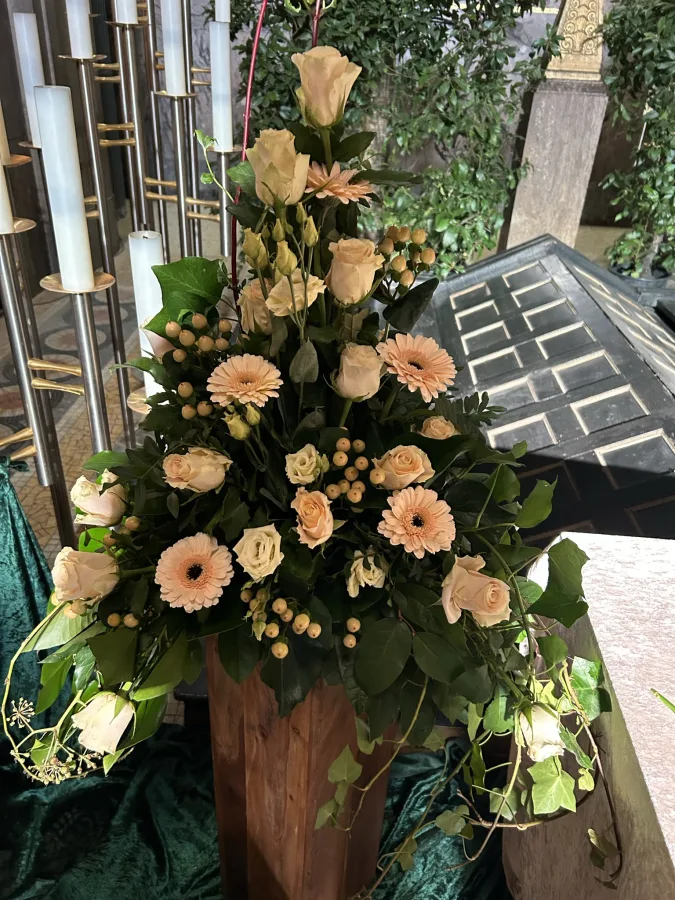 Hohes Trauergesteck mit apricotfarbenen Rosen und Gerbera auf einer Holzsäule