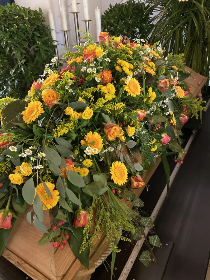 Sargbouquet mit gelben Chrysanthemen, orangen Rosen und Eukalyptus