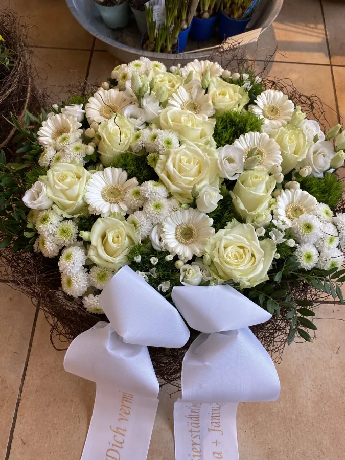 Runder Trauerstrauß aus weißen Rosen mit beschrifteten Trauerschleifen
