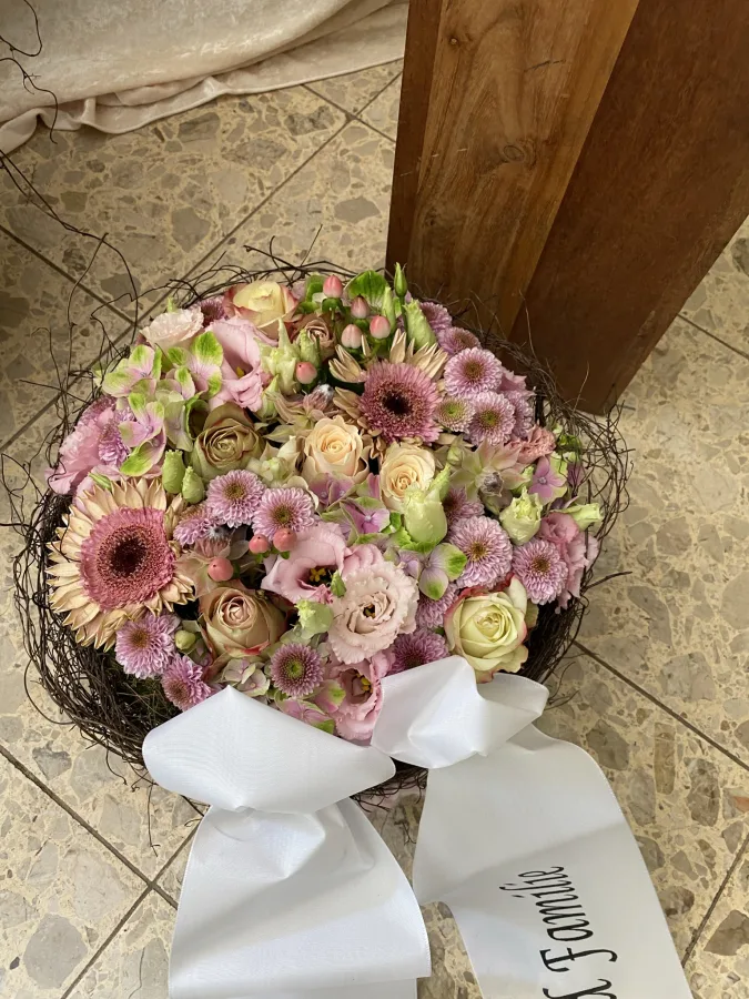 Runder Trauerstrauß mit rosa Gerbera und Rosen und beschrifteter Trauerschleife